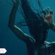 A woman with long hair in the dark underwater